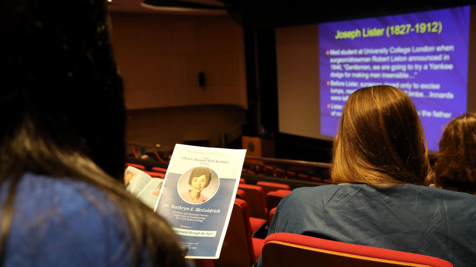 Woman holding program with image of a woman