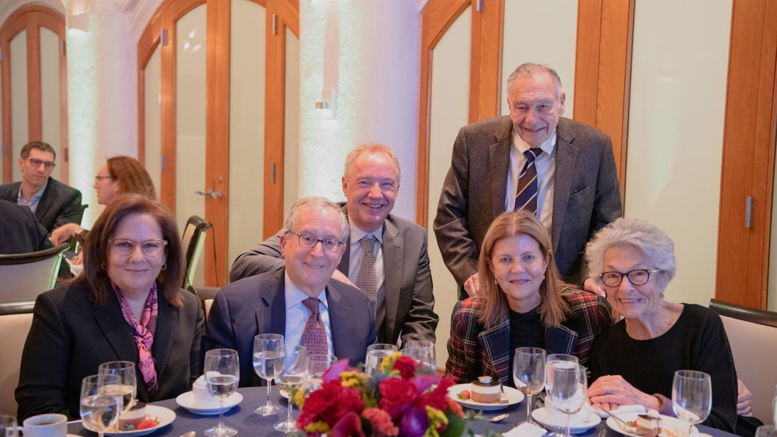 People in business attire pose at dinner table