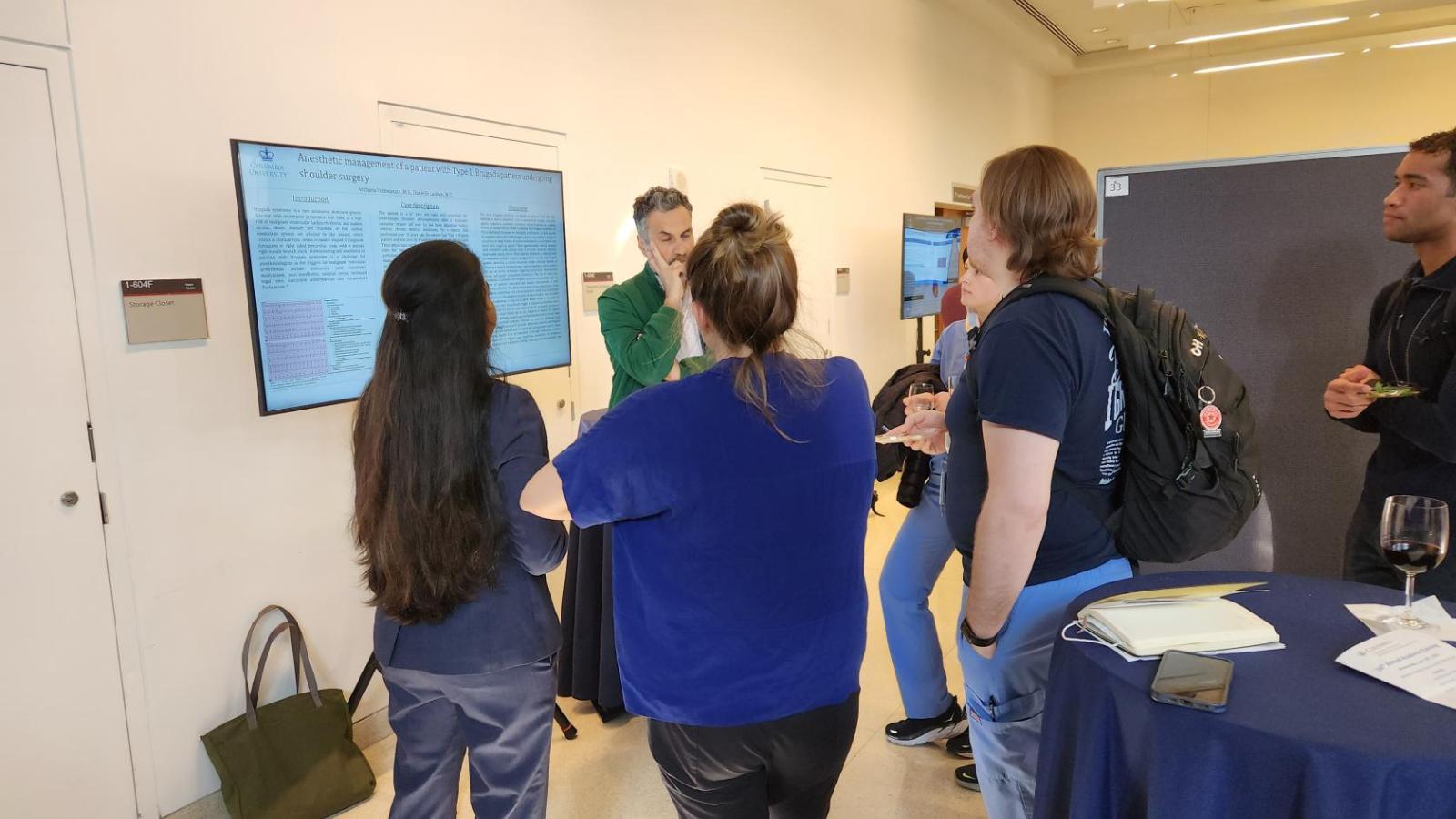 People listening to speaker standing in front of poster