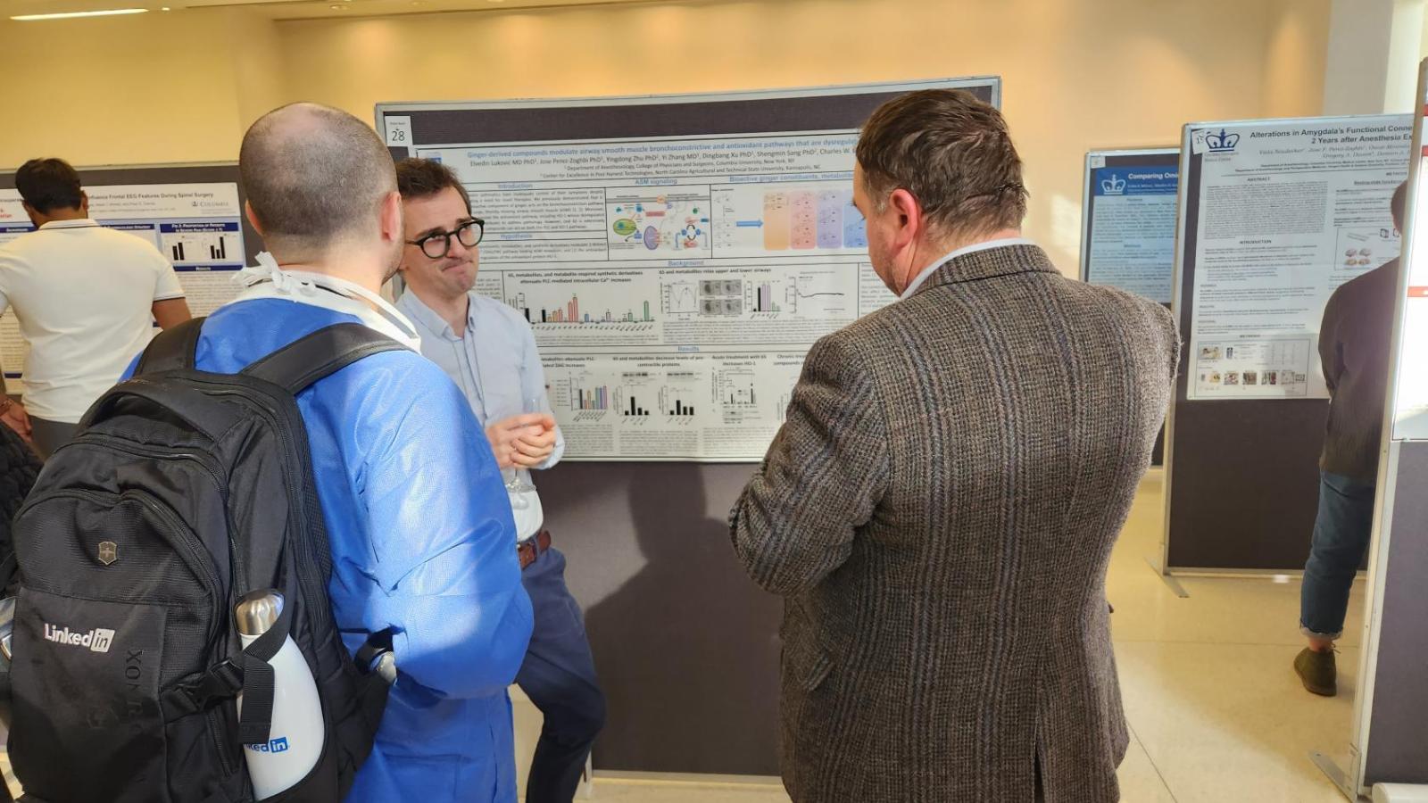 Two people listening to speaker in front of poster