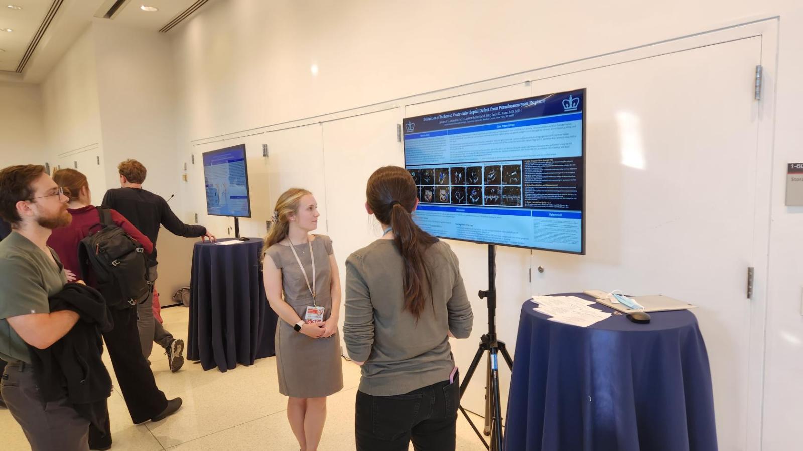 Three people looking at a poster at a conference