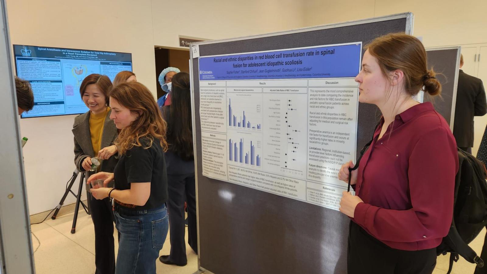 Three people looking at a poster at a conference