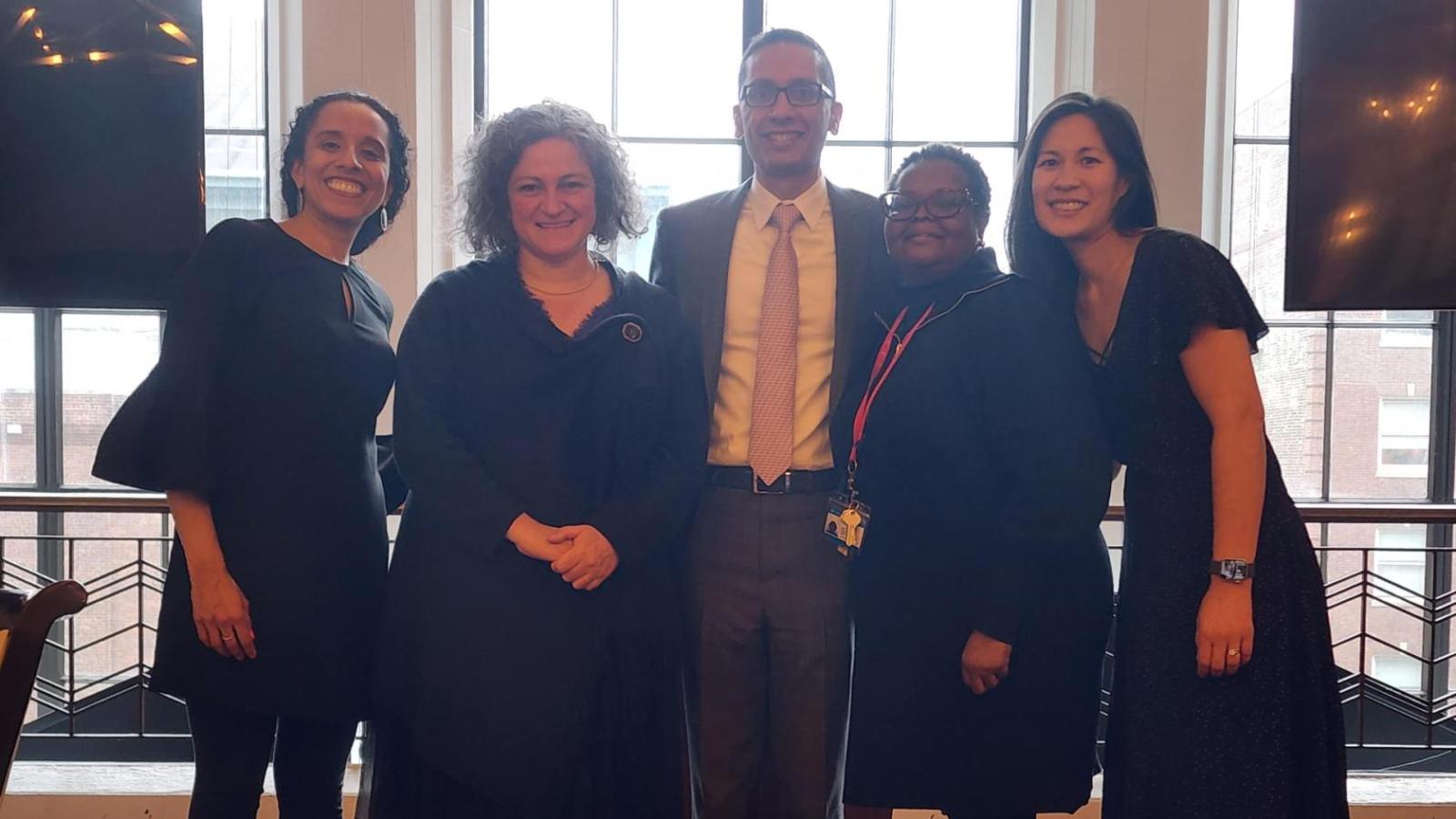 group of five standing in front of a window, one man and four women