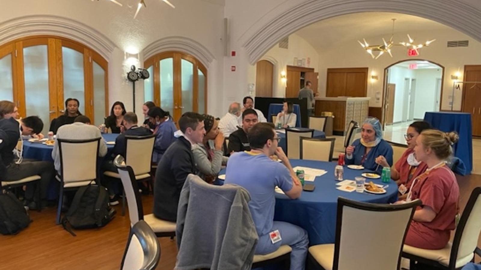 People in a room at several round tables