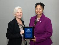 A woman handing an award plaque to another