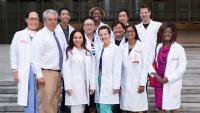 Group of practitioners in white coats standing grouped on stairs