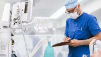 Doctor writing on clipboard in an operating room.