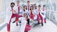 Group in white coats and raspberry coats making heart shaped hand gesture