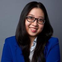 Woman, smiling, wearing glasses and blue suit, arms folded